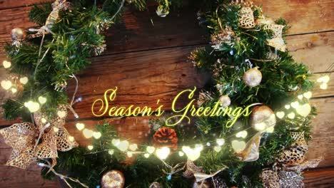 animation of seasons greetings text over wreath on wooden background