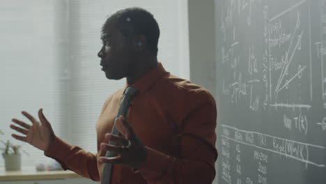 a male professor lecturing and explaining concepts on a blackboard