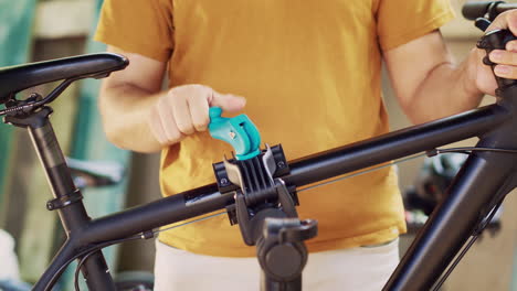 man clamps bicycle body on repair-stand