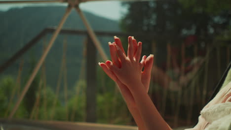 mom and daughter grasp hands in early morning light. relatives relax sitting on sunny glass balcony. caring mother looking after little child with intertwined fingers