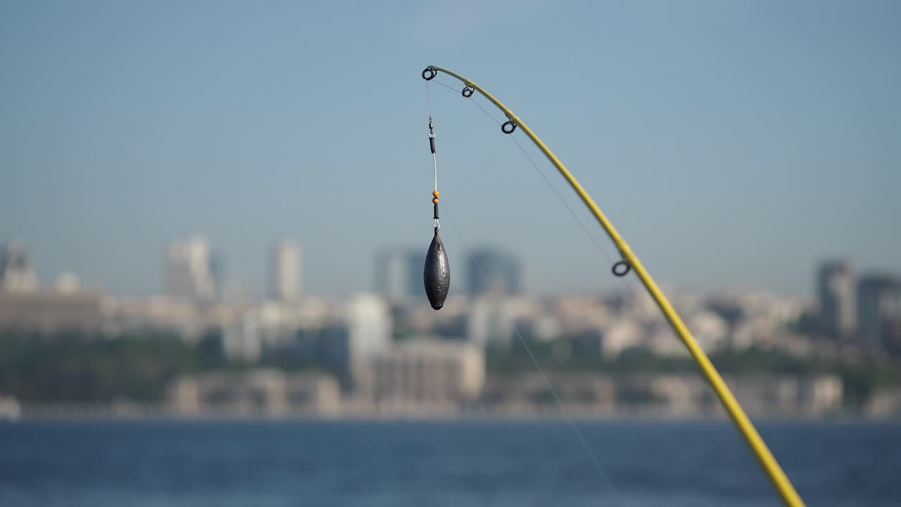 Fishing rod with sinker over the water, city view