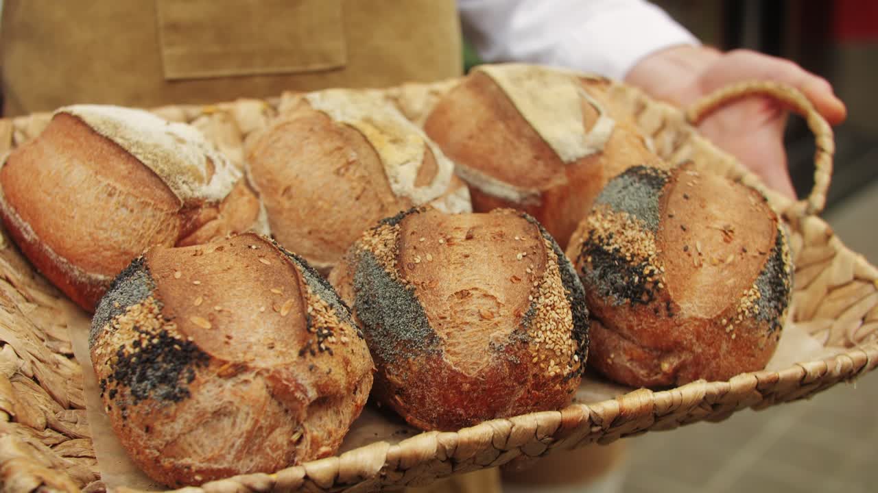 The baker holds in hands a of fresh bread with black poppy garnish on top close-up. Artisan bread is making by skill bakers using natural and high-quality ingredients. Food with health and flavour benefits.