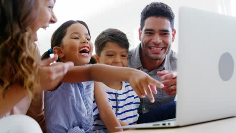 Familia-Feliz-Usando-Una-Computadora-Portátil-En-La-Sala-De-Estar