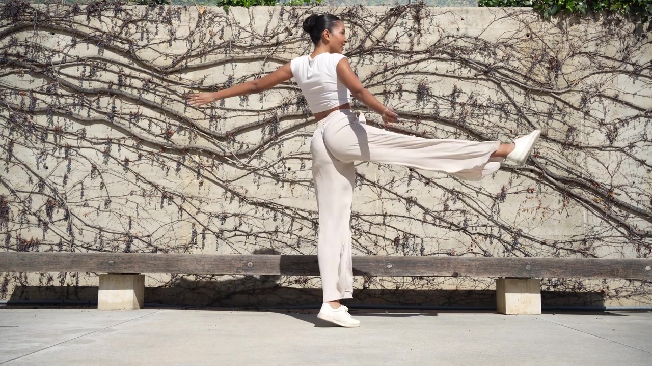 Una giovane donna alla moda che posa con sicurezza contro lo sfondo di un muro urbano artistico.