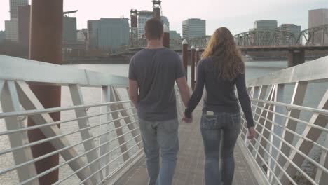 young loving couple walking their adorable dog on a bridge at sunset