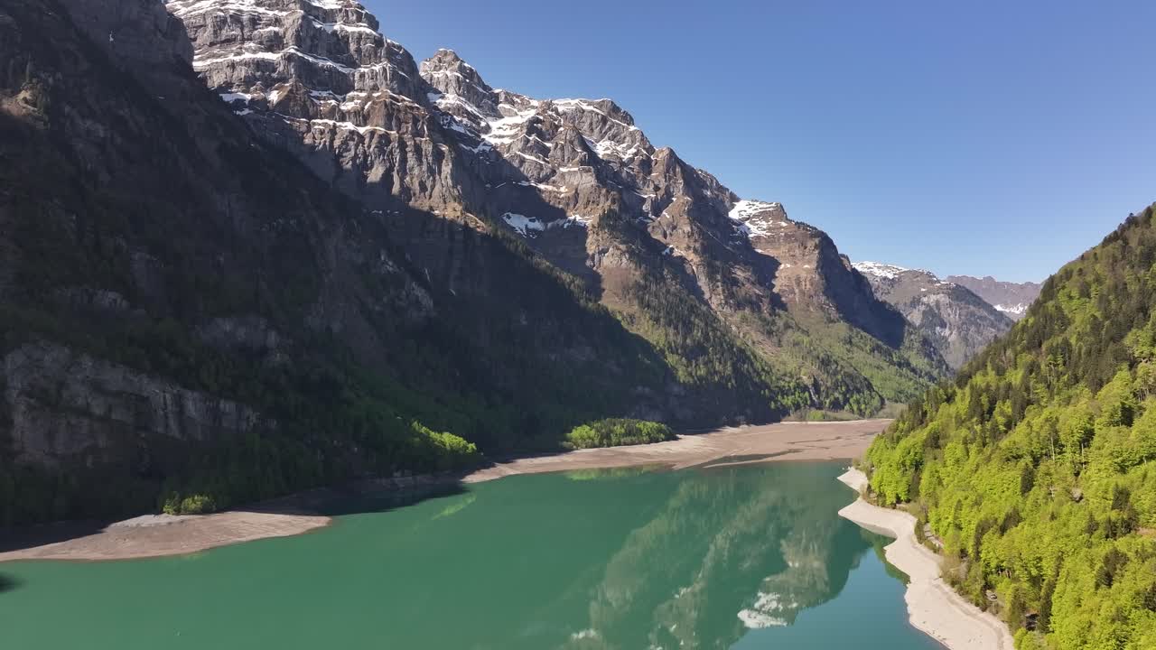 Aerial view of the Klöntalersee in the Klöntal, Glarus, Schweiz. The lake, with its turquoise water, is nestled between steep, snow-capped mountains of the Vorderglärnisch area