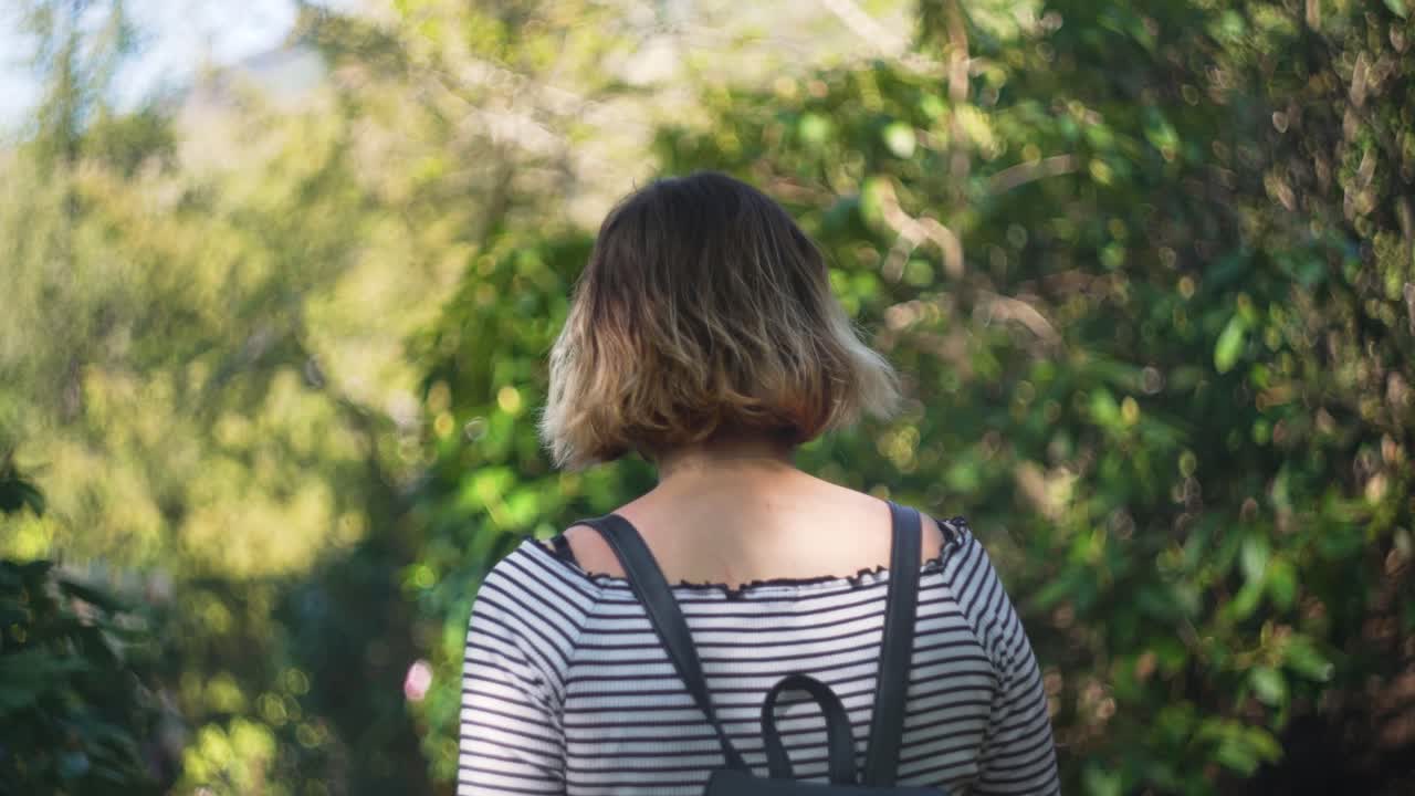 young woman walking through forest park in spring.