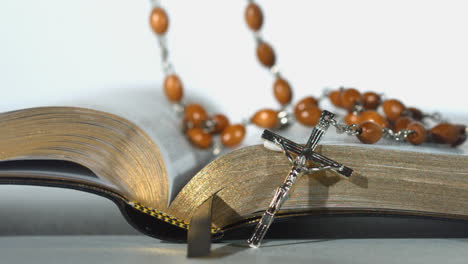 rosary beads falling on open bible on white background close up