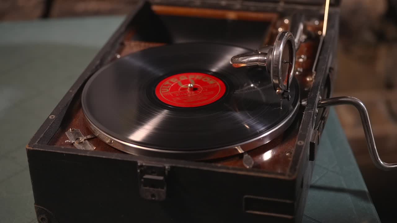 Giradischi retrò che riproduce un disco in vinile su un antico giradischi portatile. Classica tecnologia musicale analogica, esperienza di ascolto nostalgica e attrezzatura audio vintage