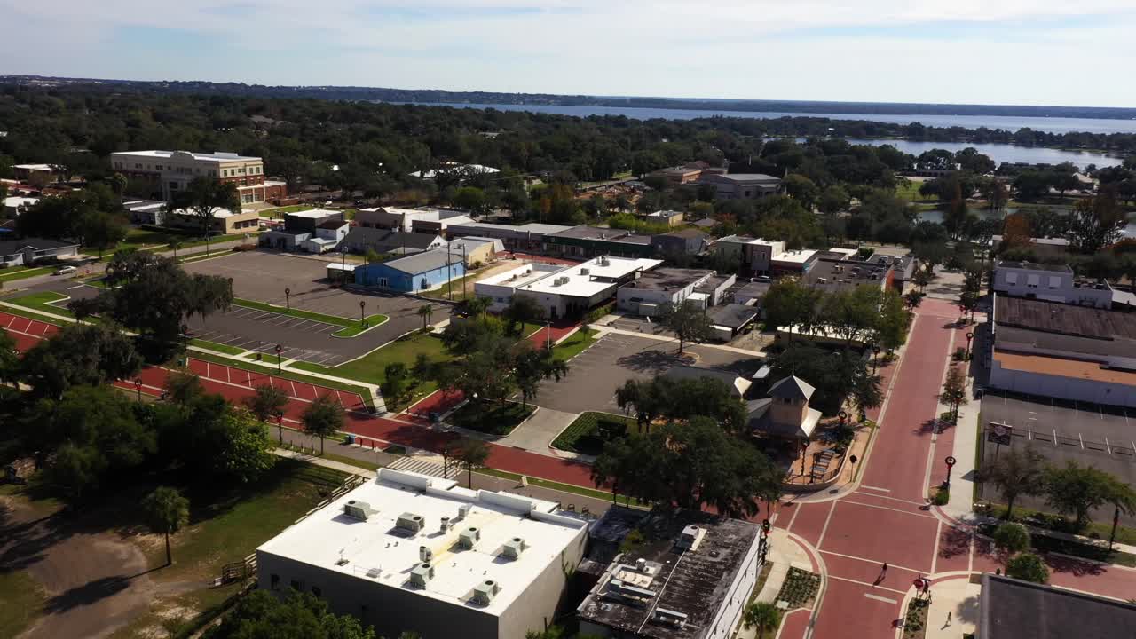 el dron orbita alrededor del estacionamiento vacío de la histórica calle principal de clermont, florida, al mediodía.