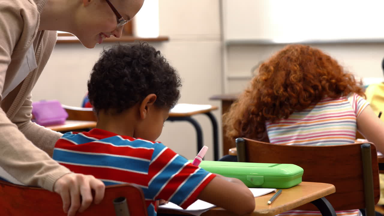 maestra ayudando a un niño pequeño durante la clase