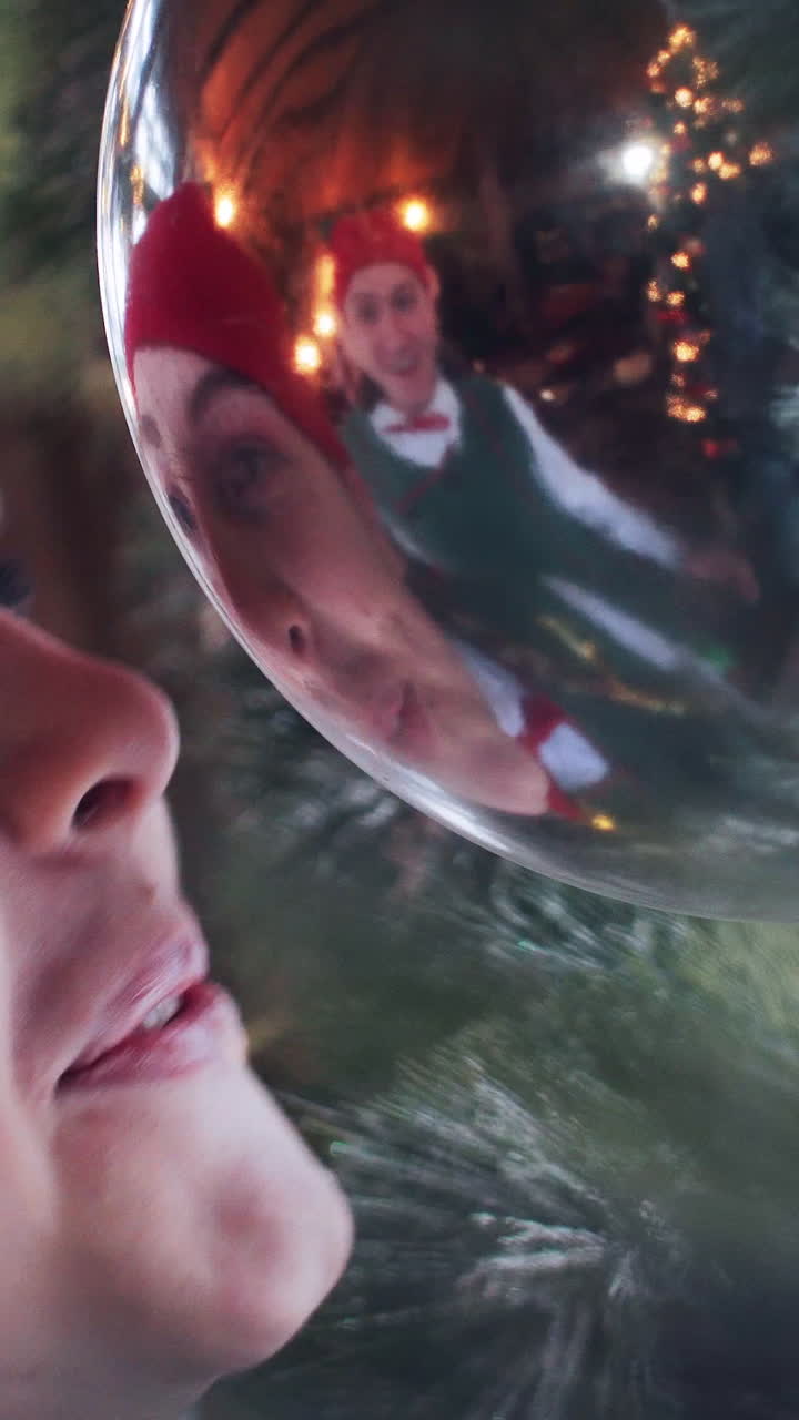 Santa Claus funny elves play with a Christmas toy that hangs by the window Vertical video