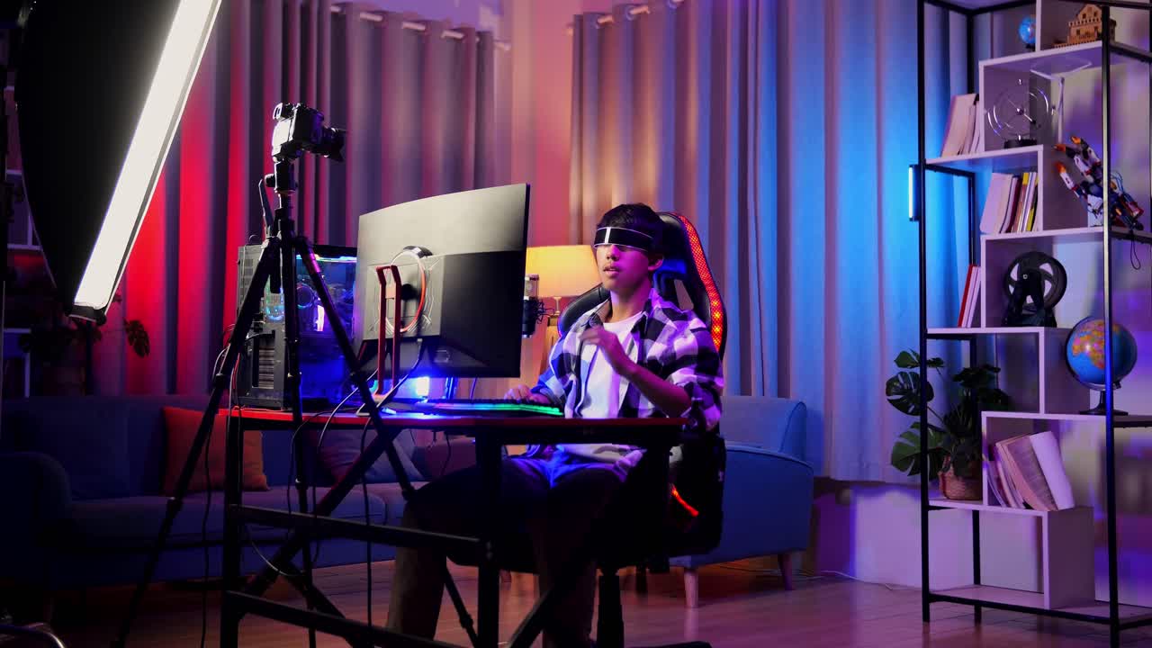 asian boy streamer jugando juego, tocando y deslizando experiencia de realidad virtual en gafas futuristas. jugador tocando panel de aire. computadora personal en el escritorio iluminada por luz de tira de led rgb