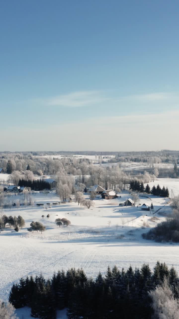 Vertical aerial drone view of multiple family country houses in rural area on a bright snow covered winter morning.