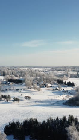 vertical aerial drone view of multiple family country houses in rural area on a bright snow covered winter morning.