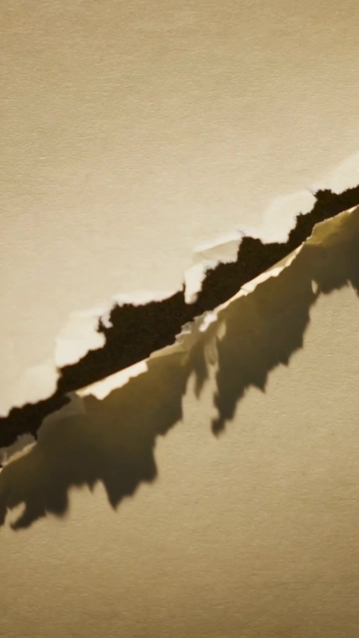 Vertical video: Opening seam causing diagonal jagged tear widening on beige sheet, showing void