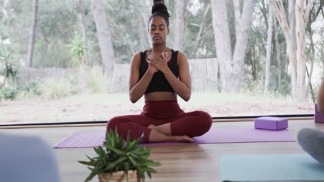 diverse women with hands on chest practicing breathing exercise in yoga studio