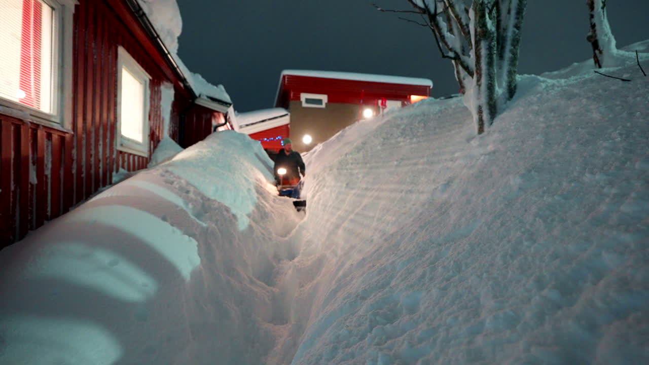 Man operates snow blower, cutting through heavy drifts of snowfall