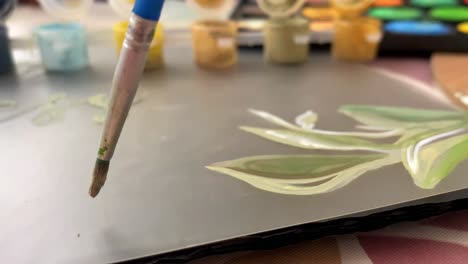 Close-up-shot-of-hands-painting-leaves-on-a-canvas