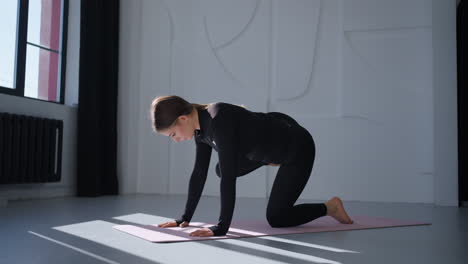 woman doing yoga exercises on mat in a studio