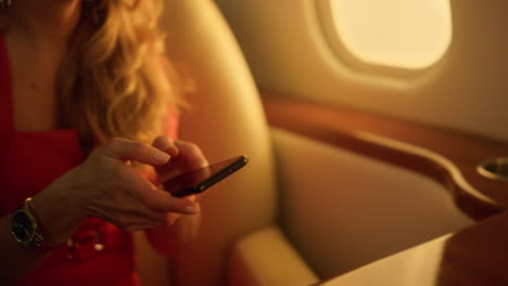 mujer de negocios escribiendo un mensaje en un teléfono inteligente. pasajero volando en un avión privado.