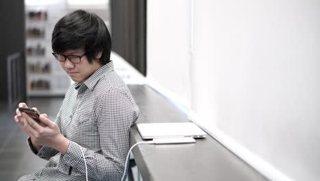 young asian business man enjoy using smartphone on social media application and playing game at break time in office. urban lifestyle in working space concept.