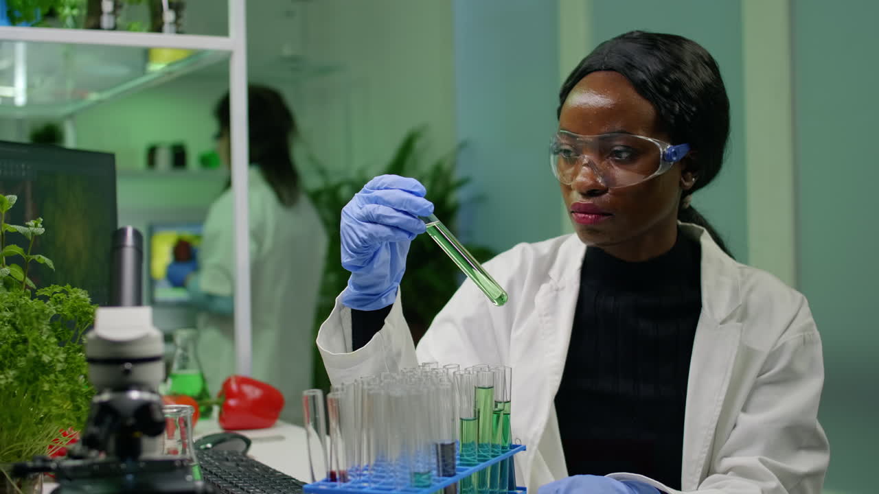 African botanist researcher checking test tubes with dna test liquid
