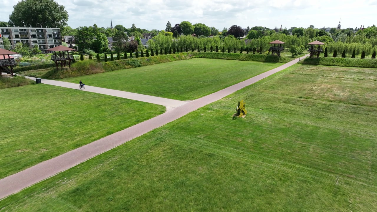 Aerial zoom in towards Matilo field, surrounded by trees, paths and the urban architecture of Leiden city.