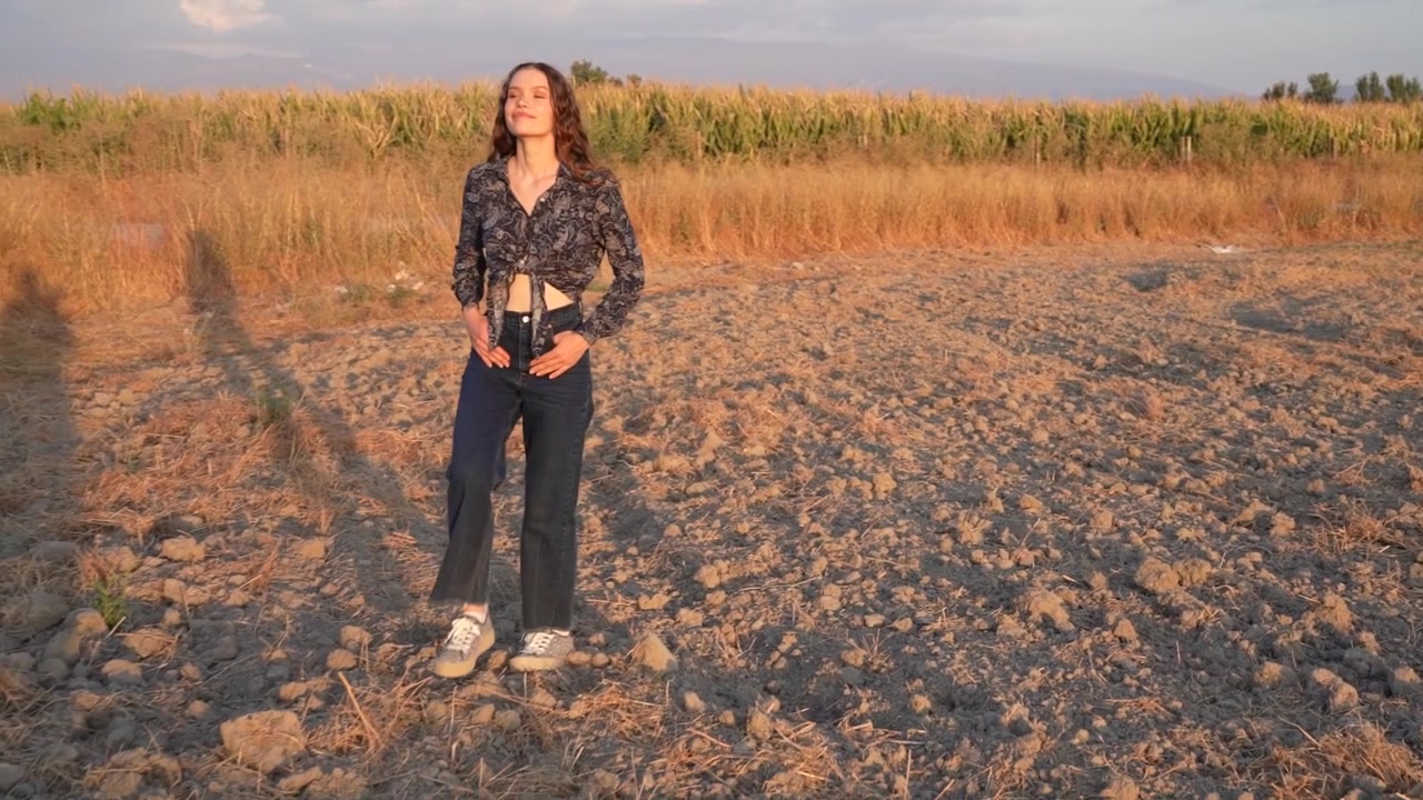 Eine fröhliche und heitere Frau spaziert an einem warmen Sommertag durch ein wunderschönes, sonnendurchflutetes Feld.