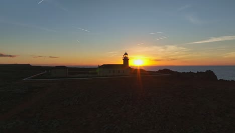 Aerial-pullback-of-sunset-at-Punta-Nati-Lighthouse-in-Menorca,-Spain