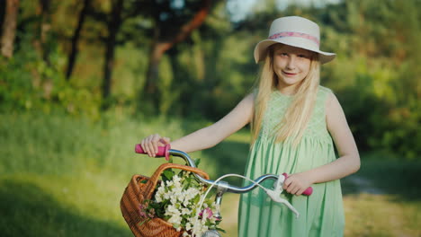 Porträt-Eines-Blonden-Mädchens-Mit-Einem-Fahrrad-Mit-Ihrem-Korb-Voller-Wildblumen-Schaut-In-Die-Kamera-4k-Video