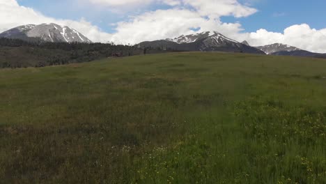 Snow-covered-rocky-mountains-and-open-hillside-fly-over-during-the-spring