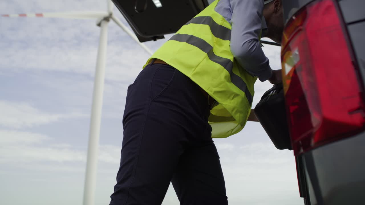 vista de ángulo bajo del ingeniero de mantenimiento caucásico sacando una caja de herramientas del coche.