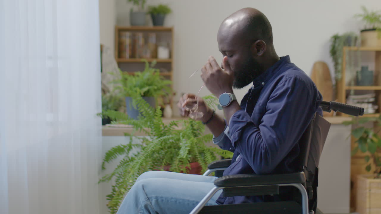 Black Man in Wheelchair Looking through Window at Home