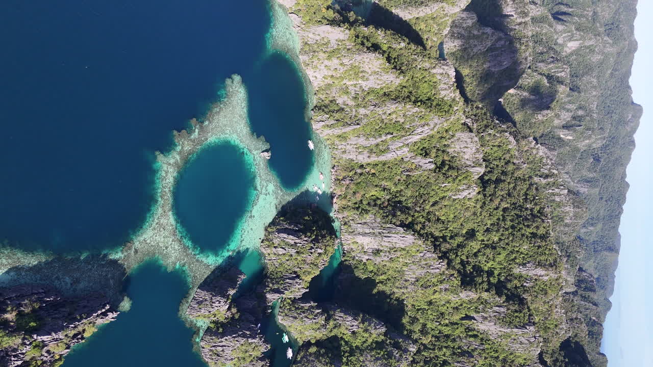 Drone view of Philippines, Coron Island’s untouched coastline, surrounded by lush forests and clear waters. Aerial view of bungalows and lagoon. Rotating drone shot. Vertical video.