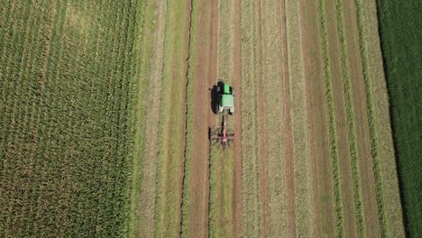 on a farm field in southwest wisconsin, a farmer rakes hay using a rotary hay rake-3