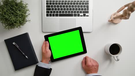 las manos de un hombre sosteniendo una tableta digital con una pantalla verde
