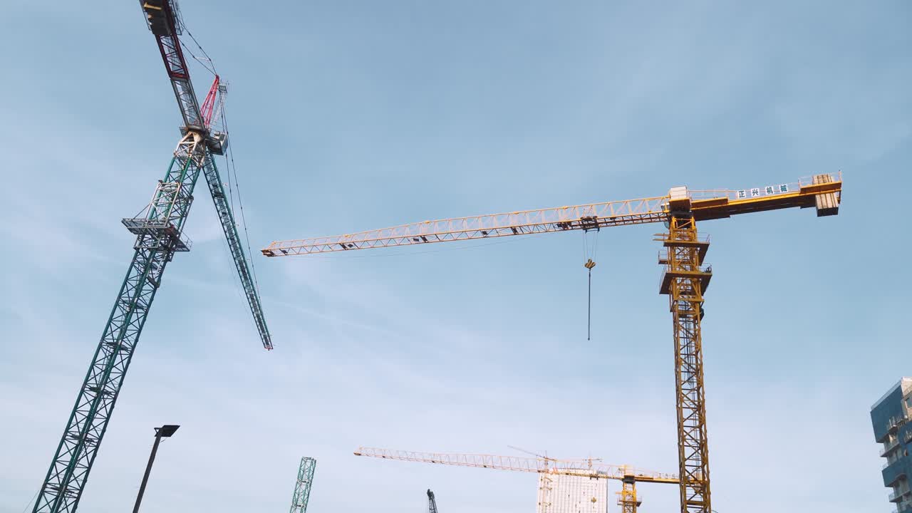 Construction site with cranes on the background of skyscrapers and blue sky.