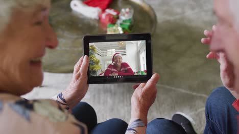 Lächelndes-älteres-Kaukasisches-Paar,-Das-Ein-Tablet-Für-Einen-Weihnachtsvideoanruf-Mit-Einer-Frau-Auf-Dem-Bildschirm-Verwendet