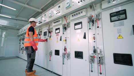 el ingeniero eléctrico que trabaja comprueba la tensión de corriente eléctrica y la sobrecarga en la parte delantera del gabinete del centro de carga o de la unidad de consumo para el mantenimiento en la sala principal del sistema de distribución de energía.
