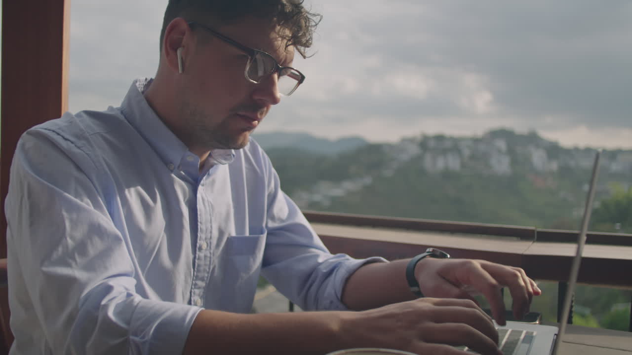 Uomo d'affari che lavora al portatile sulla terrazza di un bar di montagna