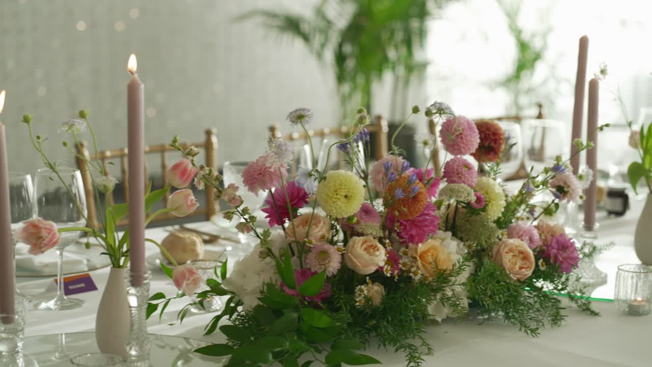 Pastellfarget blomsterdekorasjon med lys og glass på bryllupsbord i Portugal