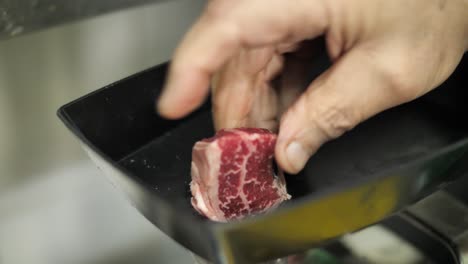 close up on hand putting raw beef meat into grinding machine to make minced meat