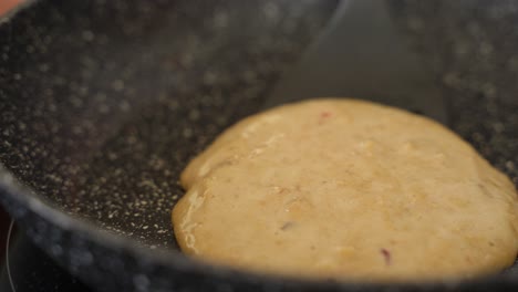 flipping crepe on frying pan with spatula in slow motion, close up