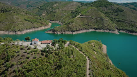 small chapel on top of a hill by a river