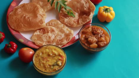 rotation chole bhature or chick pea curry and fried puri served in terracotta crockery over blue background