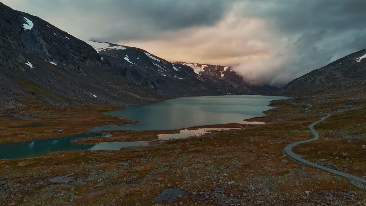 Time-lapse af autocamper parkeret i rasteplads nær bjergsø under dramatisk solnedgangshimmel, Norske højfjelde.