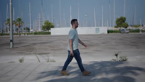 man walking in a parking lot by the marina
