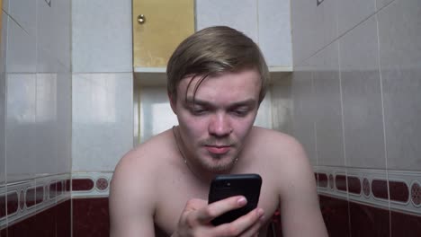 man using smartphone in a small bathroom toilet