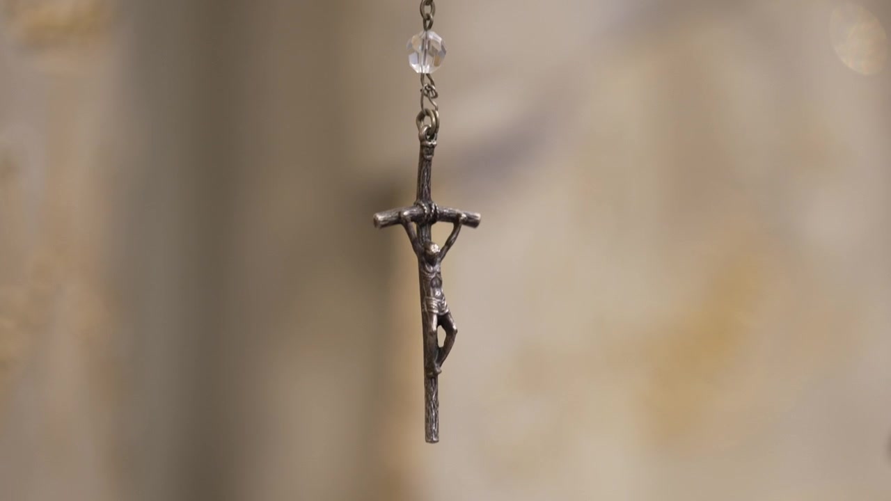 Delicato ciondolo a crocifisso in primo piano, che simboleggia fede e devozione.